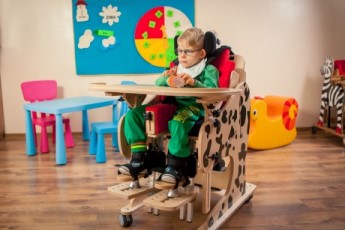 a child placed in the DALMATIAN Chair & Stander