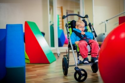 child with glasses sitting in special needs stroller model ulises evo by akses med