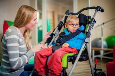 child with glasses sitting in special needs ulises evo stroller by akses med