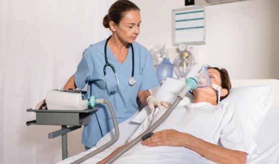 Caregiver clinician consulting a patient on a hospital bed with Resmed Stellar 150 on the table. 