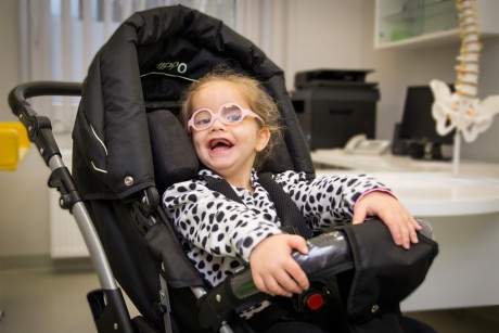 A child with disability seated in a black buggy.