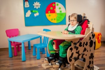 a child placed in the DALMATIAN Chair & Stander.