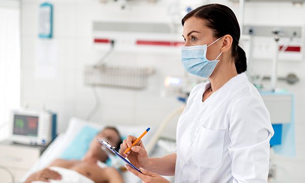 Hospital nurse treating patient on ventilator